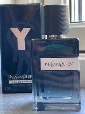 Yves Saint Laurent Y Eau de Parfum - Y Eau de Parfum från Yves Saint Laurent med stilren svart och transparent glasflaska. Doften kommer i originalkartong och flaskan har en modern, maskulin design med metallisk svart kork och tydlig Y-logga på förpackningen.