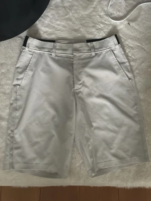 Vita golf shorts ifrån bogey&birdies - Snygga vita shorts med raka ben och bälteshällor. Shortsen har två sidofickor fram och två bakfickor, samt svarta detaljer vid midjan. Perfekta för sommardagar och har en stilren look.