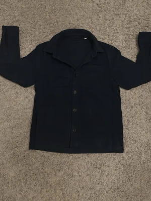 Mörkblå overshirt från D'once de la sense - Säljer just nu denna stilrena och eftertraktade Overshirten från D’once de la sense!  Storleken är S. Skick 9/10.  Tveka inte att höra av er vid minsta lilla funderingar!🤩