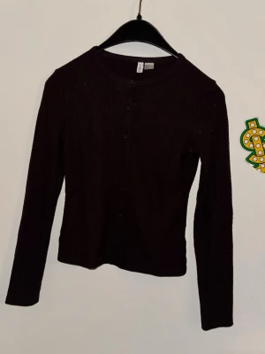 Svart ribbad kofta med knappar - Snygg svart ribbad kofta med långa ärmar och knäppning framtill. Enkel och stilren design som passar till det mesta. Perfekt att slänga över en topp eller bära stängd för en clean look.