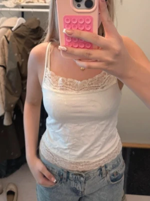 Vit spetslinnetopp från H&M Divided - Säljer en söt vit linnetopp från H&M Divided med tunna axelband och fina spetsdetaljer vid halsringning och nederkant. 