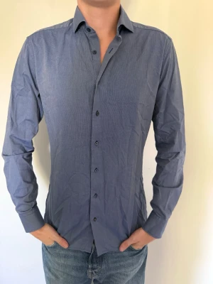 Mörk blå under skjorta från Eterna  - Snygg blå skjorta med klassisk krage och knappar framtill. Skjortan har lång ärm och en smal passform som ger en stilren look. Knappt använd, storlek 40 (L). Hör av dig om du har några frågor eller vill ha fler bilder. Pris kan diskuteras! 