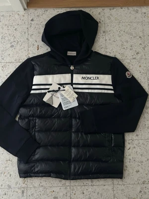 Moncler Cardigan med huva - Cardigan som passar perfekt nu när hösten närmar sig. Storlek 3 alltså M men passar även S då Moncler brukar vara små i storleken. Fraktar samma dag som köpet sker!