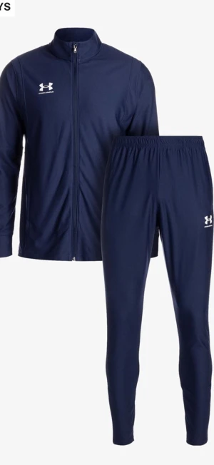 Marinblå träningsdress Under Armour - Snygg marinblå träningsdress från Under Armour med dragkedja på jackan och elastisk midja på byxorna. Setet har vita loggor på både jacka och byxa. Perfekt för träning eller chill. Materialet är mjukt och stretchigt för maximal komfort.