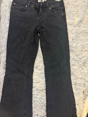 Low boot jeans 157 - Säljer ett par svarta jeans med rak passform och klassisk femficksdesign. Jeansen har normal midja och är tillverkade i ett denimtyg med lätt tvättad look. Perfekta för en avslappnad och stilren outfit. I längden SHORT.