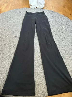 Svarta bootcut träningsbyxor OTP - Säljer ett par svarta träningsbyxor från OTP i storlek XS (32/34). Byxorna har bootcut-modell med utsvängda ben och bred linning i midjan. Perfekta för gymmet eller yoga och tillverkade i stretchigt material för maximal komfort.