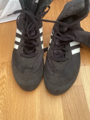 Basic svarta adidas boxningsskor. - Säljer ett par svarta adidas boxningsskor, perfekt för dig som går på boxning/börjat och vill ha bra balans och känna sig lätt på fötterna. Skorna har bra stöd vid hälen och är jätte sköna. Haft i ca 1,1/2 år  och har aldrig upptäckt problem med de. Inga defekter!