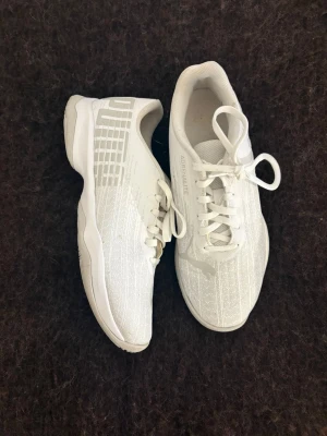 Vita sneakers från Puma - Snygga vita sneakers från Puma med texten 'ADRENALITE' på sidan och klassisk logga på ovandelen. Skorna har lågt skaft, vita snören och ovandel i mesh-liknande material som ger en sportig och fräsch look.