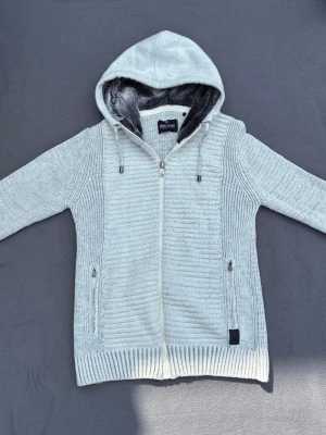 Stickad cardigan / kofta - Stickad cardigan med luva i en schysst färg. Päls i luvan och fickor med dragkedja. Fint skick, storlek M.