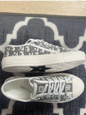 Christian Dior gråvita sneakers - Säker ett par Christian Dior (riktiga), nästan aldrig använda! Inget täcken på smuts eller något. De är i storlek 38, får med kartong från dior med skorna i. Priset kan absolut diskuteras🩷