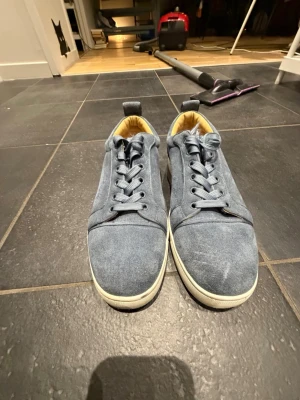 Blåa loubs  - Snygga blå sneakers i canvasmaterial med vita sulor och matchande blå skosnören. Insidan är ljusgul och skon har en klassisk låg profil med dragflik bak. Perfekta för en avslappnad och stilren look. 