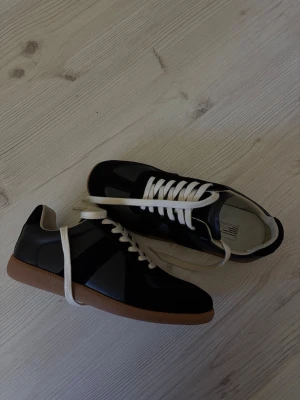 Maison margiela german army trainers - Marigila gats, härliga skor med låg sula och säljs till extremt låg pris. Svarta med vita snören och brun sula. Passar till varje aktivitet och är det perfekta vardagliga dojorna. ✨🎉 kontakta vid minsta fråga