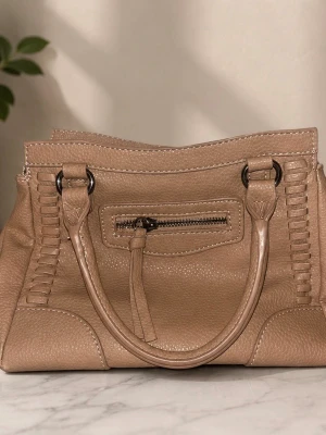 Beige handväska med detaljer - Snygg beige handväska i mjukt, strukturerat konstläder med dekorativa sömmar och flätade detaljer. Väskan har två rejäla handtag, en liten ficka med dragkedja framtill och ytterligare en dragkedjeficka på baksidan. Perfekt storlek för vardagens essentials.
