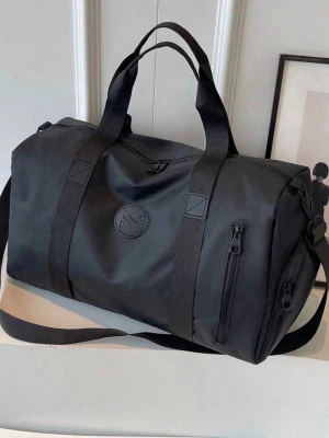 Svart sportig weekendbag med axelrem - Snygg svart weekendbag i slitstarkt tygmaterial med både handtag och justerbar axelrem. Väskan har flera dragkedjefack på utsidan och en stilren rund logga framtill. Perfekt för gymmet eller kortare resor när du vill ha plats för allt.