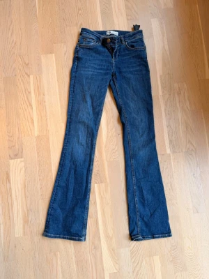 Mörkblå bootcut jeans Zara  - Snygga mörkblå bootcut jeans med klassisk femficksdesign och låg midja. Jeansen har en lätt utsvängd passform nedtill och är tillverkade i ett mjukt denimtyg. Perfekta för en avslappnad och trendig look.