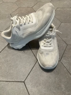 Vita sneakers från Alo - Stilrena vita sneakers från Alo med meshdetaljer och tjock sula för extra komfort. Skorna har klassisk snörning och diskret logga på sidan och plösen. Perfekta för dig som gillar en clean och sportig look.