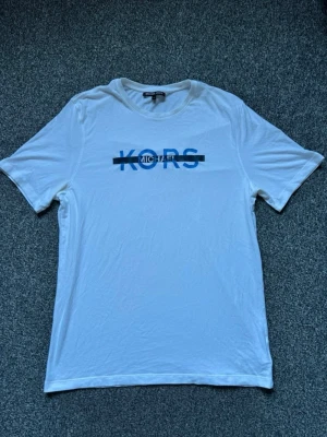Vit Michael Kors T-shirt  - Säljer en väldigt fin Michael Kors tröja i okej skick.   Trycket har tappat lite av sin färg (se bild) men övrigt är tröjan i fint skick.   Storlek: Medium i Men’s size 