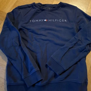Bundle- 2st sweatshirts från Tommy Hilfiger blå & grå  - Bundle-2 stycken sweatshirts från Tommy Hilfiger med klassisk logga broderad på bröstet. Tröjan har rund halsringning, ribbade muddar vid ärmslut och nederkant samt mjukt material på insidan. Perfekt för en avslappnad och stilren look. En mörkblå och en grå. Passar 170-175cl 