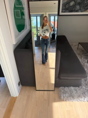 Blå bootcut jeans med hög midja - Säljer ett par klassiska blå bootcut jeans med hög midja och lätt slitning. Jeansen har en figurnära passform upptill och utsvängda ben. Perfekta till en avslappnad och trendig look. Materialet är denim i bomull.