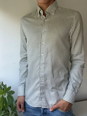 Randig långärmad skjorta - En 100% Bomull Twofold Super Cotton Skjorta från Stenströms. Passform Slimline. Nypris 1699kr. Knappt använd! En mycket kvalitativ skjorta med dobby-/krypervävd randning som ger ett väldigt elegant uttryck. Pärlknappar. Väldigt mjuk och skön på.  Perfekt kontorsskjorta som funkar både m kavaj elr mer avslappnat i chinos o jeans. Storlek 40 cm / 15½.  Kom med frågor!🙌 (Kan gå ner i pris vid köp av ett paket😉) Mått: A Bröst: 50 cm B Axlar: 43 cm C Längd: 72 cm