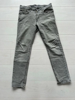 Levi's 502 slim fit jeans Grå - Levis 502, vilket är slim fit. Storlek≈ 30/29.5 (egentligen 30/32 men de är förkortade, se sista bilden med jämförelse med 30 i längd).             Finns en lagning på vänster     bakficka, men lagningen är väldigt snyggt gjord. Det är bara att fråga om du har funderingar eller vill ha fler bilder:)