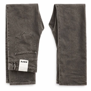 Hope Rush Jeans  - Gråtvättade jeans från HOPE med en avslappnad loose fit och stilren washed finish. Ett mångsidigt plagg som passar både en minimalistisk och mer avslappnad look.  Storlek: 36 Passform: Loose fit Skick: Nya Färg: Washed Grey / Charcoal Märke: HOPE Äkthet: 100% äkta  Alla produkter hos Archive NO21 är noggrant utvalda och garanterat autentiska.HOPE – Washed Grey Loose Jeans  Gråtvättade jeans från HOPE med en avslappnad loose fit och stilren washed finish. Ett mångs