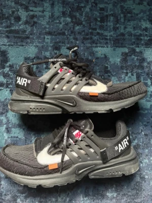 Nike x Off-White Presto svarta sneakers - Säljer ett par Nike x Off-White Presto sneakers i svart med vita detaljer . Skorna har mesh-överdel, plastdetaljer och Off-White signaturer som orange tag och text på skosnören. Medföljer original skokartong och ett par neon orangea snören! Storlek 46, men sitter som 44 då modellen är väldigt liten i storleken. Kan passa 43 också!