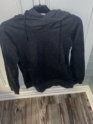 Mörkgrå hoodie - En enkel och stilren mörkgrå hoodie med huva och svarta dragsnören.