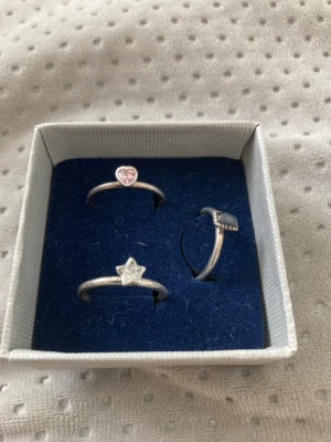Söta silverringar med stjärna och hjärta - Tre tunna silver ringar i olika former: en med en liten stjärna, en med ett rosa hjärta och en med en svart rektangulär sten. Perfekta för att mixa och matcha till din egen stil. Alla ringar har en tempel 925. En kostar 200 eller 350 för alla. 