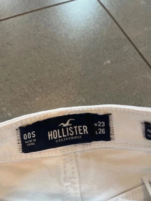 Vita high waist shorts Hollister - Säljer ett par vita shorts från Hollister med råa kanter och klassisk femficksdesign. De har knapp och dragkedja framtill samt bälteshällor. Perfekta för sommaren och riktigt snygga till crop tops eller oversized t-shirts.