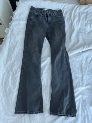 Mörkgrå bootcut jeans - Snygga mörkgrå jeans med bootcut passform och klassisk femficksdesign. Jeansen har hög midja och raka ben som slutar i en lätt utsvängning. Tillverkade i ett mjukt denimtyg som ger en avslappnad look.