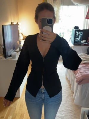 Svart v-ringad cardigan från Nelly - Snygg svart långärmad topp i storlek xxs från Nelly med v-ringning och figurnära passform. Superfin topp/tröja som jag tyvärr aldrig haft användning av!🩷