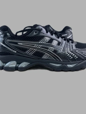 Svarta Asics Gel-Kayano 14 sneakers - Säljer ett par svarta Asics Gel-Kayano 14 sneakers med silvriga detaljer. Skorna har en sportig design med mesh- och syntetmaterial, samt den klassiska Asics-loggan på sidan. Sulan är stötdämpande och ger grym komfort till vardags.