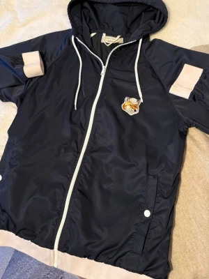 Marinblå vindjacka Maison Kitsuné - Snygg marinblå vindjacka från Maison Kitsuné. Ej för salu i Sverige och kan bara köpas i Japan, väldigt limiterad och exclusivt. I väldigt bra skick storlek M men passar S bra också