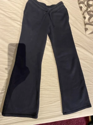 Svarta mjukisbyxor från Gina Tricot - Svarta mjukisbyxor från Gina Tricot med utsvängda ben och dragsko i midjan. Tillverkade i mjukt och bekvämt material, perfekta för en avslappnad stil. Klassisk modell utan tryck eller detaljer.