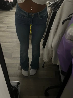 Blå utsvängda jeans med klassisk look stl xs - Snygga blå utsvängda jeans med klassisk femficksdesign. Jeansen har normal midja, ljus tvätt och en läderpatch bak i midjan. Perfekta för dig som gillar en tidlös och avslappnad stil. Materialet är slitstarkt denim i bomull.