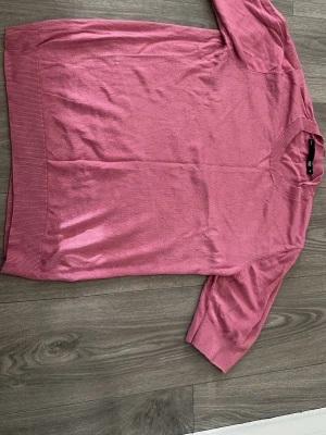 Rosa stickad tröja med kort ärm - Säljer en rosa stickad topp med rund hals och korta ärmar. Toppen har ribbade kanter vid hals, ärmslut och nederkant. Perfekt för dig som gillar en enkel men snygg stil.