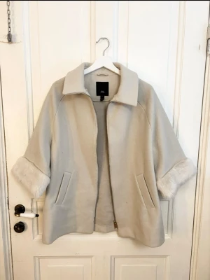 Ljusbeige kappa med fuskpälsdetaljer - River Island  - Superfin beige jacka från River Island med trendiga trekvartsärmar och mjuka pälsdetaljer. En riktig ikonisk Y2K-modell som ger en lyxig och stilren look. Superbekväm och perfekt att bära under höst, vinter och tidig vår.  Mycket fint skick och ett riktigt statement-plagg 🤍
