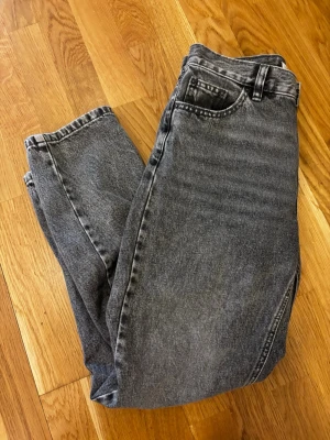 Grå pull and bear jeans med hög midja - Säljer ett par grå jeans från pull and bear med hög midja och raka ben. Jeansen har klassisk femficksmodell, bälteshällor och stängs med knapp och dragkedja. Perfekta för en avslappnad och trendig look. Jättefint skick. Storlek 36. Jag är typ 165cm lång.
