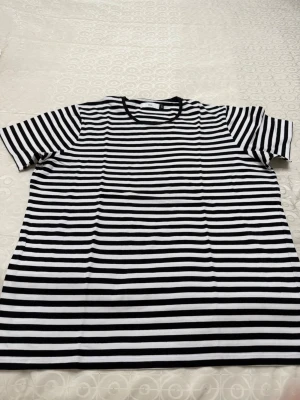 Randig svartvit t-shirt - Säljer en klassisk svartvit randig t-shirt med rund hals och korta ärmar. T-shirten har en relaxed passform och är tillverkad i mjuk bomull, perfekt för en enkel och stilren look.