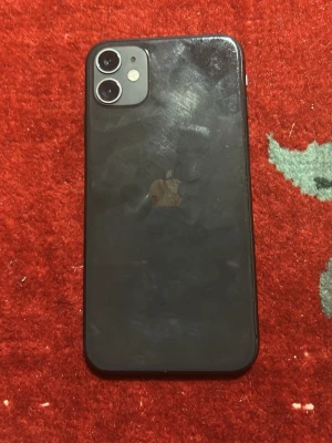 Svart iPhone med dubbla kameror - Säljer en svart iPhone 11 med rundade hörn och dubbla kameror på baksidan. Telefonen har en stilren glasbaksida och den klassiska Apple-loggan. Perfekt för dig som vill ha en snygg och modern smartphone.