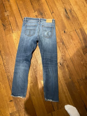 Blå raka jeans med rå kant - Ett par tiger off sweden jeans i modellen Rex med väldigt snygg Wash. Storlek 32:30. Har en snus ring på bakfickan.