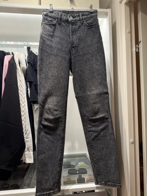 Svarta raka jeans med tvättad look - Snygga svarta jeans med tvättad, lite gråaktig finish och raka ben. Klassisk femficksmodell med hög midja och dragkedja. Perfekta för en avslappnad och trendig stil. Materialet är denim, vilket ger en skön och slitstark känsla.