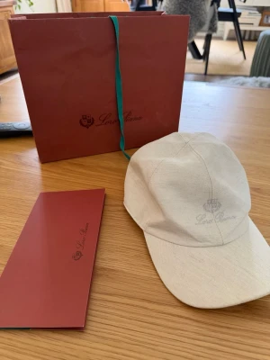 Loro Piana Baseball Cap i linne  - Loro Piana Baseball Cap i bomull/linne, storlek M. Made in Italy.  Skick: i princip nyskick. Använd två gånger, sedan legat kvar i originalförpackningen. Säljer den helt enkelt för att jag inte använder den.  Köpt på Harrods i London 4 maj 2024 för £325 (ca 4 200 kr idag). Originalkvitto, kartong, påse och skötselhäfte medföljer – allt du ser på bilderna ingår. Motsvarande modell kostar idag runt 5 000–5 500 kr ny.  Detaljer: - 59% bomull / 41% linne, foder i 100% linne med rutigt mönster - Just