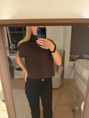 Brun croppad polotopp - Snygg brun croppad polotopp med korta ärmar och rak passform. Perfekt att styla med höga jeans eller kjol för en trendig look. Tjockare material som ger en stilren siluett och passar till många outfits.