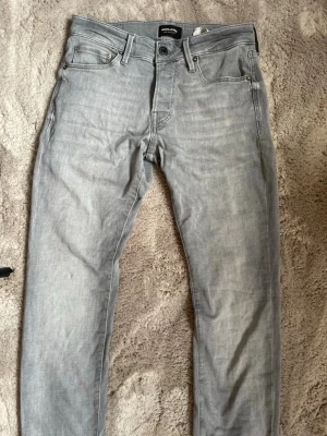 Ljusgrå slim fit jeans - Snygga ljusgrå jeans i slim fit-modell med klassisk femficksdesign och dragkedjegylf.