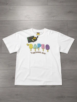 Bape Popsicle Tee Storlek M - Bape popsicle tee från säsongen SS23 i färgen vit och storlek M. Aldrig använd, helt ny med taggar som följer med vid köp! Perfekt om du är ute efter en streetwear look, hiphop stil eller bara till vardagstilfällen.