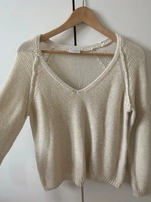 Beige stickad tröja med v-ringning - Säljer en otroligt snygg vit stickad tröja från vila!! Den är i storlek S i jättebra skick!! Den är lite guldskimrig eftersom det har små gultrådar. Fritt fram att testa skicka prisförslag. Skickar snabbt. Snabbt köp uppskattas 💗