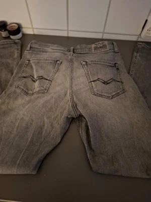 Replay 14a - Säljer ett par grå tvättade jeans med raka ben och snygga broderade bakfickor. Jeansen har klassisk femficksdesign och är gjorda i denim. Perfekta för en avslappnad och trendig look.