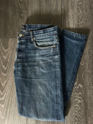 Blå raka jeans från A.P.C. - Säljer ett par sällsynta A.P.C jeans med riktigt snygg fade, De är standard modellen med raka ben. Säljer då de börjar bli för små för mig. Storleken är W30.   Inga märkvärdiga deffekter utöver att de har hål i båda fickorna men går att laga. Bara att skriva vid minsta fundering!